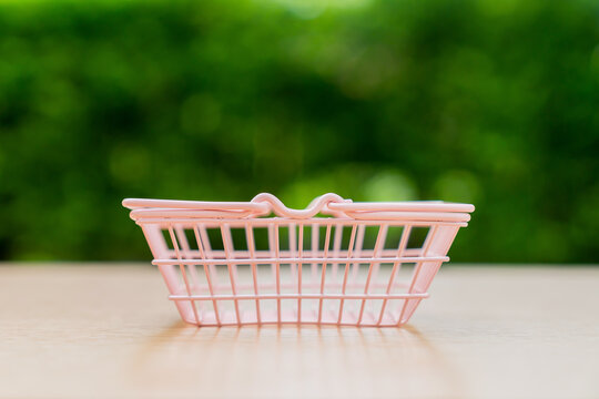 Pink shopping basket on a table, retail, consumer spending, and purchasing decisions.