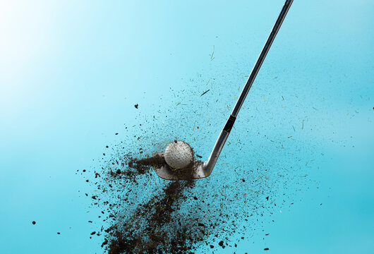 Golf ball explode from Tee off. Golfer hit ball with metal iron club to grass soil explosion on green. Golf club hit ball on green tee off with grass flying scatter. Blue Sky background isolated