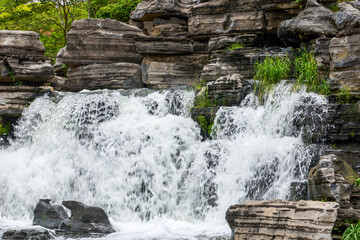 Artificial waterfall flowing between cascading gray rocks © Steve