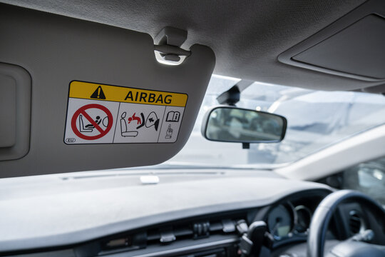 A car sun visor pulled down on the passenger side, displaying an&nbsp;airbag safety warning sticker.&nbsp;The warning label details precautions regarding rear-facing child seats and active front airbags.&nbsp;