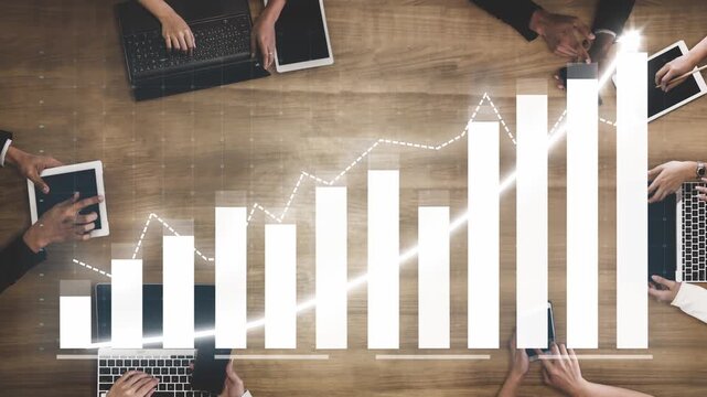 A dynamic business meeting with multiple hands using digital devices on a wooden table, showcasing a growth chart indicating financial progress and collaboration. Copula