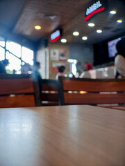 Fototapeta premium Blurry interior view of a fast food restaurant with wooden tables and warm lighting.