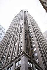 Fototapeta premium Low angle view of a tall beige skyscraper with many windows against an overcast sky