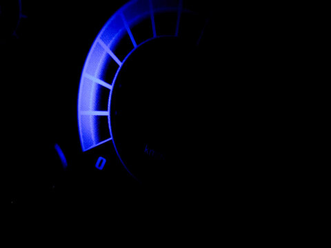 Glowing blue dashboard gauge meter on black background.