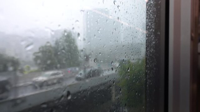 Raindrops covering train window with blurred urban view outside in Tokyo