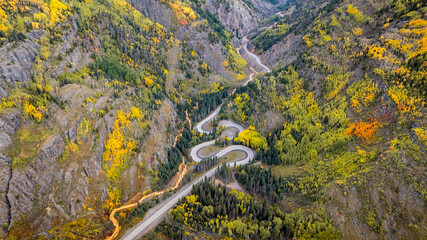 Obraz premium Bird's eye view of winding road switchbacks on Million Dollar Highway in Colorado San Juan Mountains landscape with fall foliage trees during autumn season near Ouray morning sunrise 