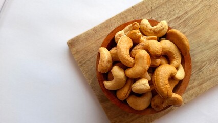 Fototapeta premium Photo of a collection of cashew nuts in a wooden bowl on a wooden cutting board