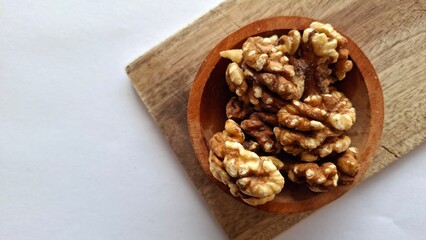 Fototapeta premium Photo of a collection of walnuts in a wooden bowl on a wooden cutting board