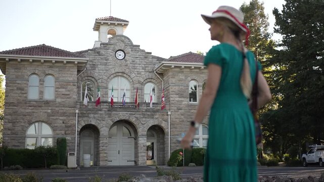 A senior woman enjoys a sunny day while walking near the historic City Hall in Sonoma California, showing her happiness.