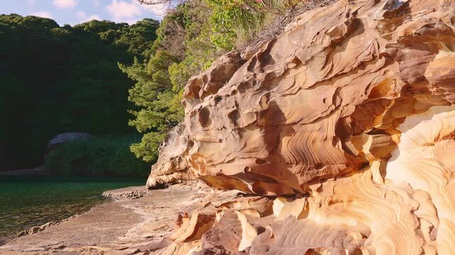 風化した独特の岩肌と透明感のあるエメラルドグリーンの海辺風景