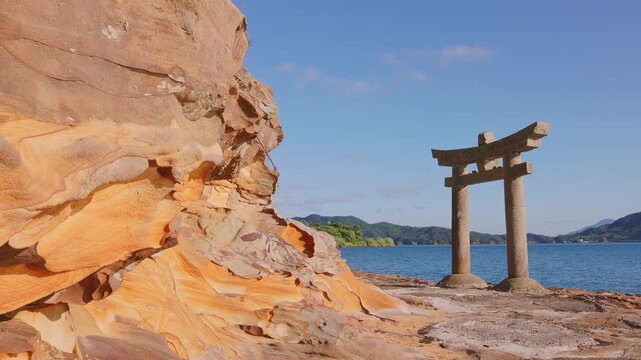 神秘的な砂岩の岩肌と青い海にたたずむ石造りの鳥居（和田津美神社）