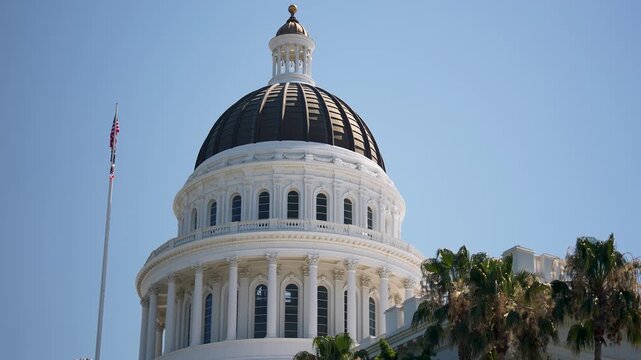 The video shows the California Capitol building in Sacramento at sunrise. The dome is visible against a clear morning sky.