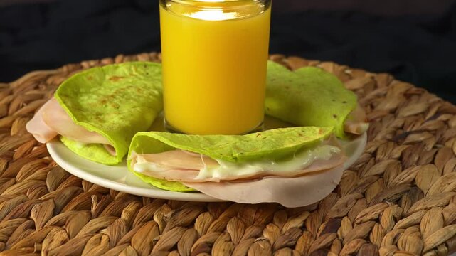 Close up of green nopal tortilla quesadillas with ham and cheese served with fresh orange juice