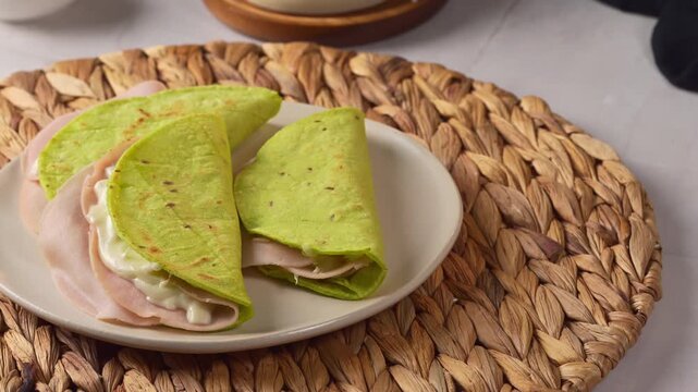 Fresh nopal quesadillas filled with ham and melted cheese on a woven placemat