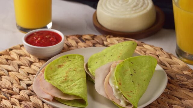 Traditional Mexican quesadillas prepared with green nopal tortillas, ham and melted cheese accompanied by red salsa and fresh juice
