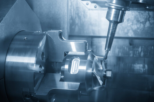 5 axis CNC milling machine machining automotive part with ball nose end mill in blue tone lighting