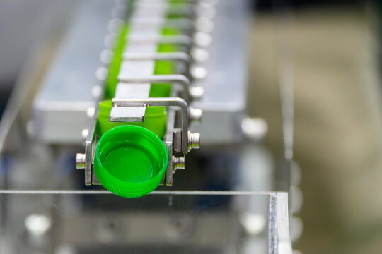 Green plastic bottle caps on conveyor belt after mass production process