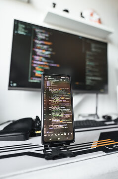 Professional software engineering desk with large display, smartphone showing code and organized equipment. Comfortable workstation reflects efficient programming, testing and digital innovation.