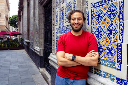 Smiling young man posing by a traditional tile wall in Mexico City