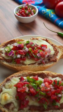 Aerial view of delicious Mexican snacks molletes with melted cheese beans and spicy pico de gallo