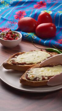 Placing a traditional mollete with cheese and refried beans on a white plate