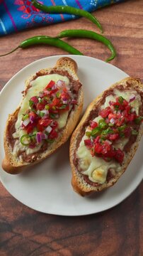 Top down shot of traditional Mexican open-faced sandwiches also known as molletes on wooden table