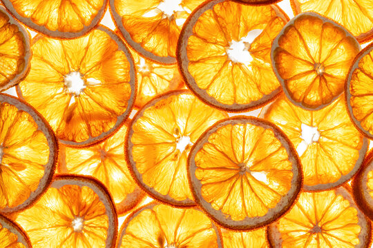Abstract glowing background of translucent orange fruit slices by backlight. Aesthetic food Natural geometric pattern. Vibrant texture for summer design, menus, and wellness layouts, yellow gradient.