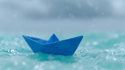 A paper origami boat floating gracefully on bright turquoise ocean water surface