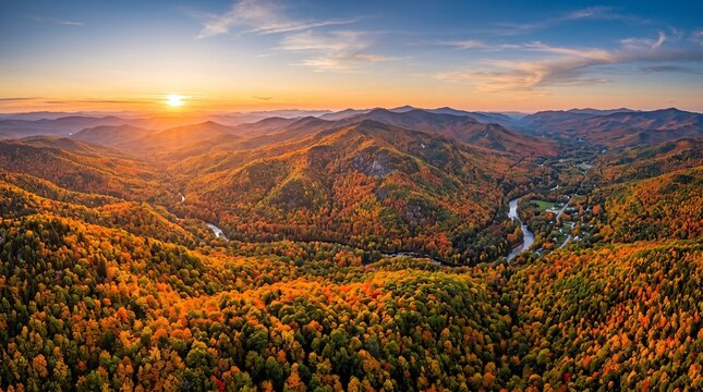 Mountains covered in a tapestry of autumn forest colors surround a winding river valley as the sun begins to set behind the distant peaks casting a warm golden glow over the vast wilderness landscape.