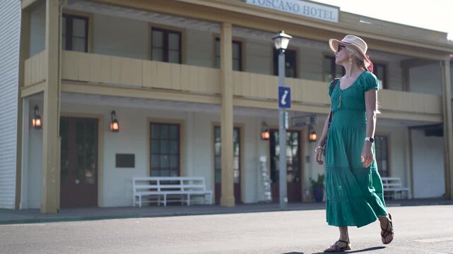 Senior woman walks happily by historic buildings in Sonoma California just after sunrise on a beautiful morning
