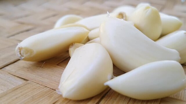 Organic peeled garlic cloves scattered on a rustic wooden table with natural lighting