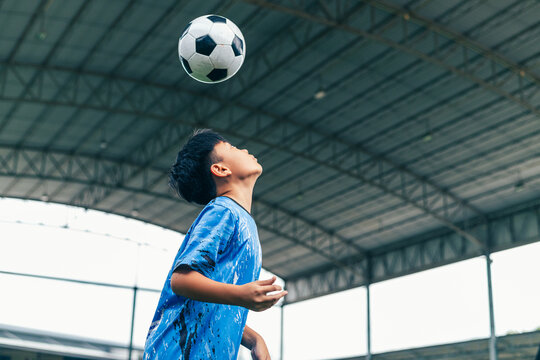 Young boy juggling soccer ball with foot at indoor field.