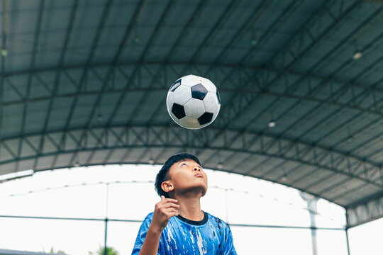 Young boy juggling soccer ball with foot at indoor field.