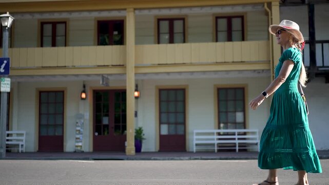 A mature woman walks by the Toscano Hotel and Sonoma Barracks on a warm morning just after sunrise in Sonoma, California.