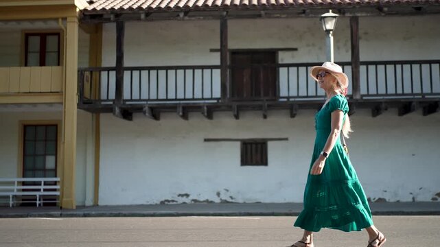 Happy senior woman walks beside historic buildings in Sonoma California on a bright morning right after the sunrise.