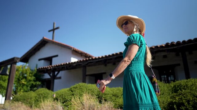 Senior woman smiles and walks around the historic Mission church San Francisco Solano de Sonoma enjoying the scenery on a sunny day