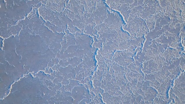 Top-down aerial view of Larnaca Salt Lake in Cyprus. Cracked white salt patterns create an abstract natural texture.