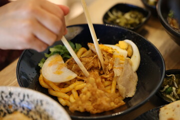 Obraz na płótnie Canvas Close Up of Person Eating Asian Noodle Bowl with Chopsticks