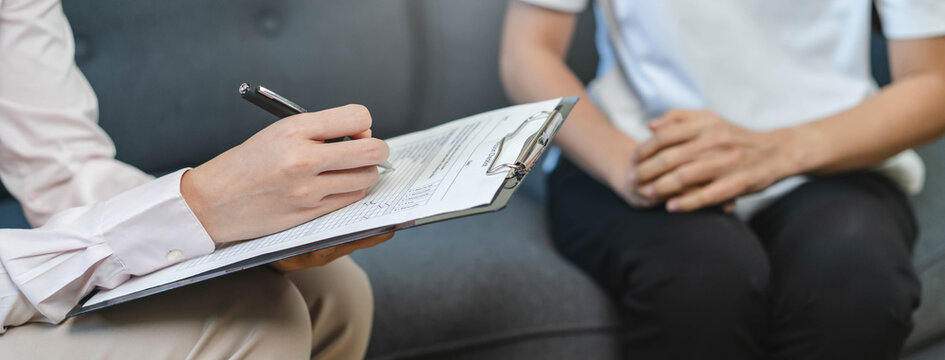 Close up medical banner of a professional female psychologist holding clipboard during therapy counseling session with an anxious patient