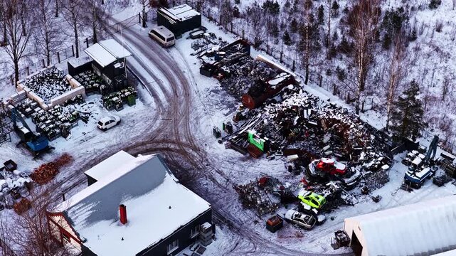 Aerial perspective of a large scrap yard with discarded vehicles and metal waste in winter