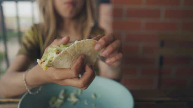 Hands holding a fresh tortilla wrap filled with lettuce and vegetables