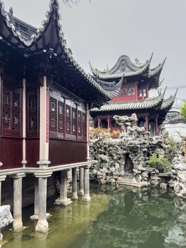 Wooden pavilions with tiled roofs beside pond at Yu Garden, Shanghai, China in spring