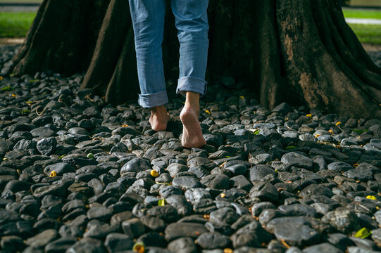 Barefoot walking on natural gravel for grounding practice in forest retreat. Mindful living, stress relief, holistic wellness, relaxation and emotional wellbeing. Self care, balance. Nature connection