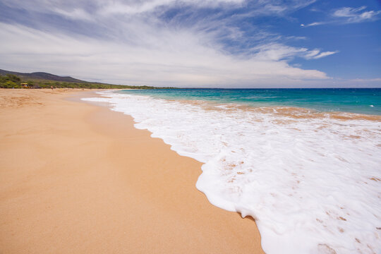 Sunny beach in Hawaii with golden sand, clear water under a bright sky