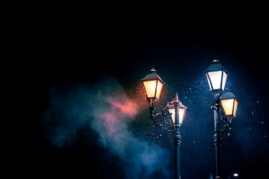 Illuminated street lamps pierce the darkness, casting a warm glow amidst a snowy night, creating a serene atmosphere.