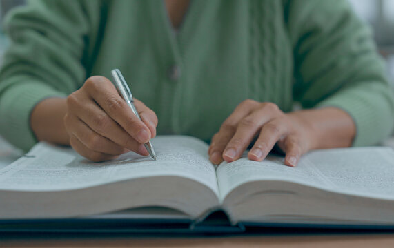 Asian woman reading book at library.