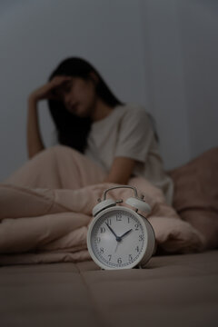 asian woman in bed late trying to sleep suffering insomnia, sleepless or scared in a nightmare, looking sad worried and stressed. Tired and headache or migraine waking up in the middle of the night.