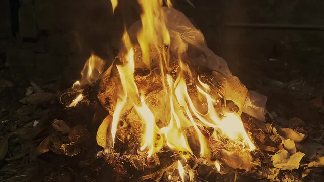 Destructive fire burning secret documents and paper waste in dark environment