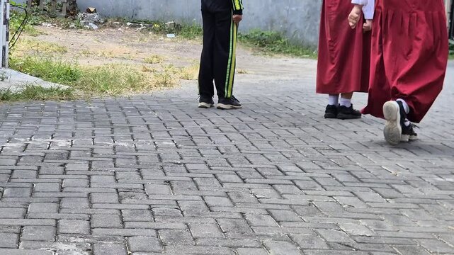 Low angle shot of Indonesian elementary school students feet walking on paved ground in red and white uniform