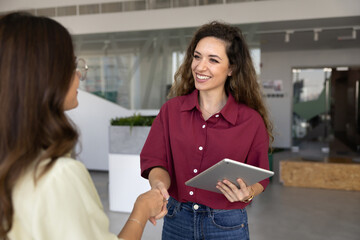 Fototapeta premium Client handshaking consultant manager holding digital tablet in office, expressing respect, thanking for professional assistance, confirming deal, concluding agreement. Partnership, business meeting